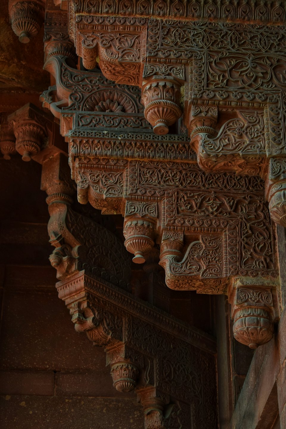 Elaborate intagli floreali su un antico muro di arenaria rovinato dal tempo.