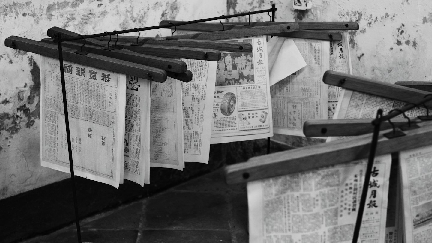 Documenti storici con scrittura dell'Asia orientale appesi su rastrelliere di legno.