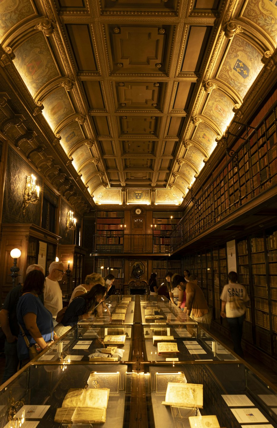 Visitatori esaminano documenti storici esposti all'interno di un archivio di biblioteca ornato.